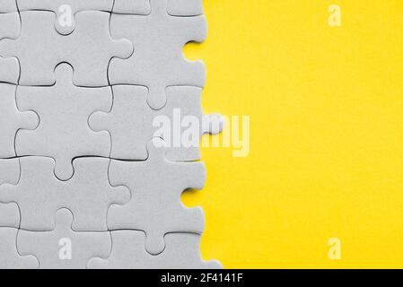 Demonstrating trendy Color of the Year 2021. Illuminating Yellow and Ultimate Gray. Duotone. Multiple grey puzzle pieces put together without one Stock Photo
