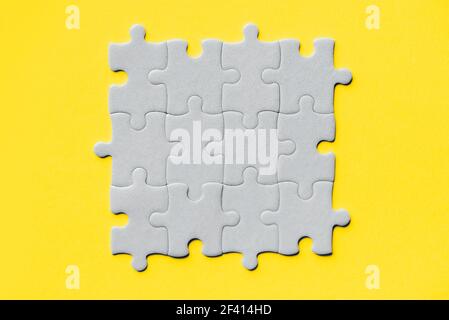 Demonstrating trendy Color of the Year 2021. Illuminating Yellow and Ultimate Gray. Duotone. Multiple grey puzzle pieces put together without one Stock Photo
