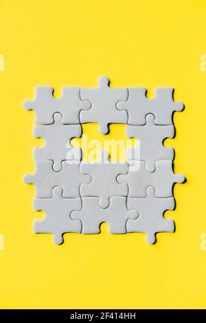 Demonstrating trendy Color of the Year 2021. Illuminating Yellow and Ultimate Gray. Duotone. Multiple grey puzzle pieces put together without one Stock Photo