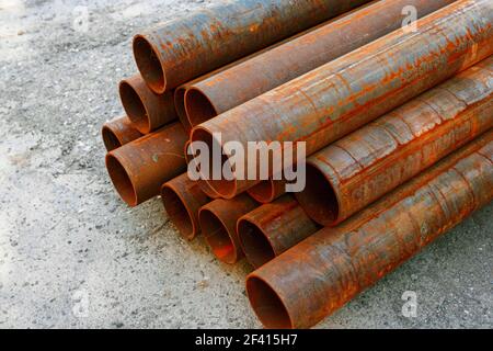 Iron pipes covered with rust in stack on ground in warehouse. Iron pipes covered with rust in stack Stock Photo