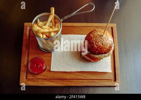 Fresh delicious halal burger with french fries, tomato sauce on the wooden plate top view.. Delicious burger with french fries, tomato sauce on the wooden plate top view. Stock Photo