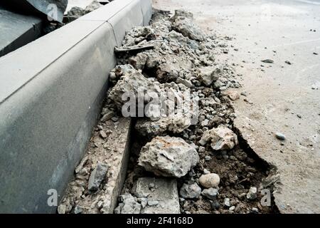 Heaps of demolished asphalt lying on the sidewalk near the pit for installing a curb. Broken asphalt. A hole in the road surface. Repair of road work. Copyspace.. Heaps of demolished asphalt lying on the sidewalk near the pit for installing a curb. Broken asphalt. A hole in the road surface. Repair of road work Stock Photo