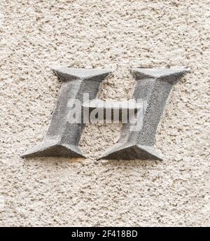 Large letter H on roughly plastered wall Stock Photo