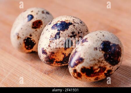 Three quail eggs on wooden board in row. Three quail eggs on wooden board Stock Photo