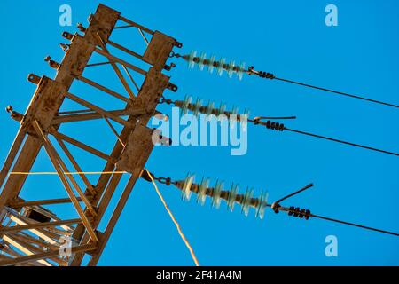 High voltage transmission power tower with glass insulators and wires against blue sky. High voltage transmission power tower with glass insulators and wires against sky Stock Photo