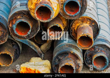 Water Pipeline repair. Large rusty steel pipe with insulation on the construction site in a plastic tube wrapper lying on the yard in a bunch horizontally. Rusty old pipeline stacked up. Water Pipeline repair. Large rusty steel pipe with insulation on the construction site in a plastic tube wrapper lying on the yard a bunch horizontally. Rusty old pipeline stacked up Stock Photo