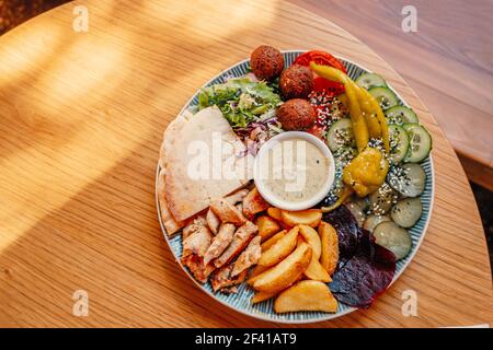 Dish of palestinian or israeli food - falafel, pita and vegetables with souse, shot with copyspace.. Dish of palestinian or israeli food - falafel, pita and vegetables Stock Photo