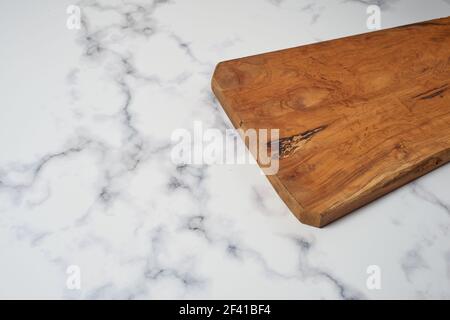 Wooden kitchen board on white marble kitchen surface, ready to cut and prepare food. With space for text. Stock Photo