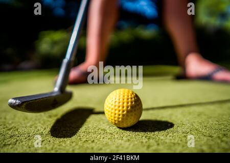 Mini Golf yellow ball with a bat near the hole at sunset Stock Photo