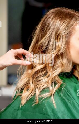 Side view of hands of female hairdresser styling hair of a blonde woman in a hair salon Stock Photo