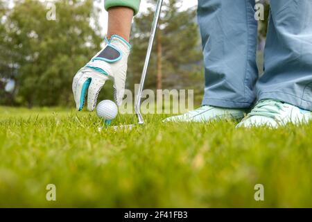 Hand in glove placing golf ball on tee Stock Photo