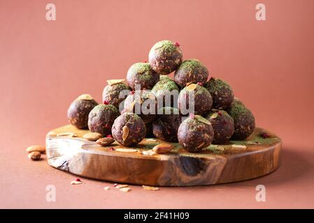 Raw energy balls with matcha tea powder on wooden board on beige background. Raw vegan, vegetarian sweets. Sugar free, gluten free, lactose free Stock Photo