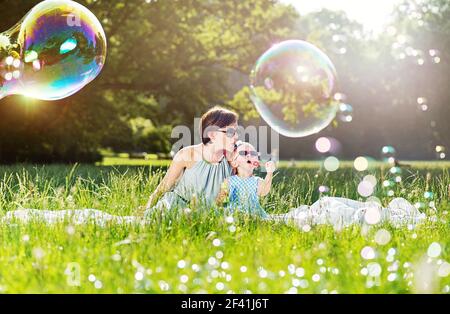 Mother and daughter family time, blowing large soap-bubbles Stock Photo