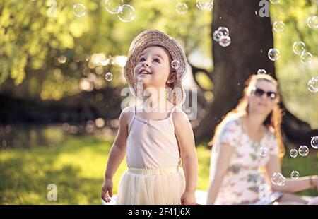 Mother and daughter looking at the shining soap bubbles Stock Photo