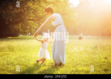 Attractive mother dancing with her daughter on the meadow Stock Photo
