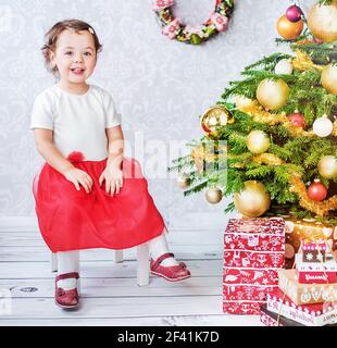 Cute little child sitting nesxt to the Christmas tree Stock Photo