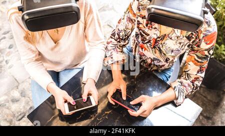 Girl friends playing on vr glasses outdoor - Virtual reality and wearable tech concept with young people having fun together with headset goggles Stock Photo