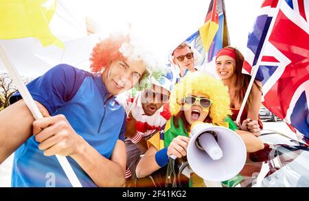 Football supporter fans friends cheering after soccer cup match hanging around with car and flags - Young people group with multicolored t-shirts Stock Photo