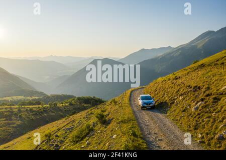 Front aerial view of four wheel car driving up a mountain road in beautiful hill landscape Stock Photo