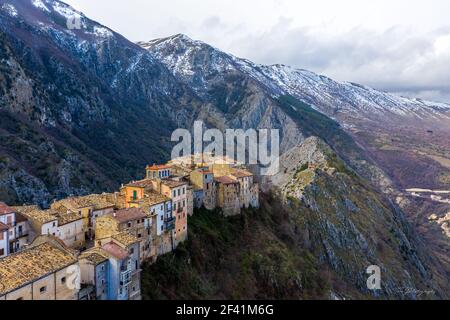 aerial view of medieval quarters in Abruzzo atop a mountain peak, with a light dusting of snow adorning the surrounding hills Stock Photo