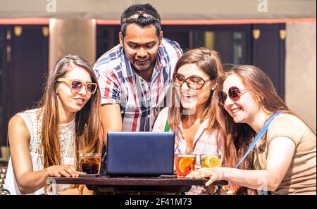 Multiracial friends at cocktail bar having fun with laptop - Connected community of young students people using pc on social media networks Stock Photo