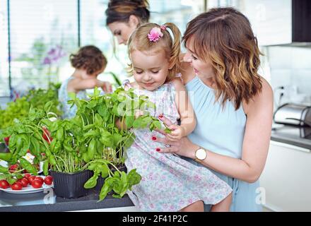 Young mothers with their beloved children in the bright, summer kitchen Stock Photo