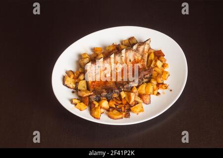 Dinner plate presentation of pork ribs cooked in a spicy vegetable sauce on a white plate. Tasty homemade meat recipes. Stock Photo