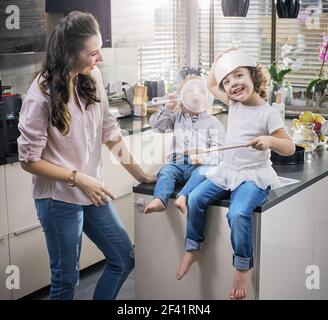 Chherful mother watching her children having fun in the kitchen Stock Photo