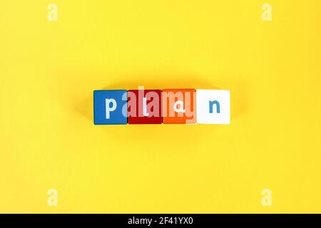 Word Plan made from colored wooden blocks. Painted cubes with letters on yellow background. Conceptual photo. Business concept. Top view. Stock Photo