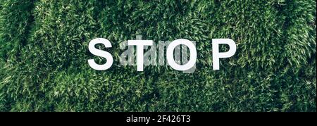 Word Stop on moss, green grass background. Top view. Copy space. Banner. Biophilia concept. Nature backdrop. stop environmental pollution Stock Photo