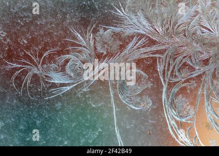 Jack Frost etchings on the window, with a colourful background. Stock Photo