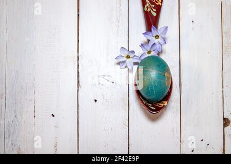 Delicate Spring Starflowers around a natural coloured egg laid on a wooden spoon. Easter flatlay on a white shabby chic background. Stock Photo