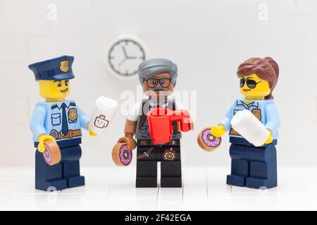 Tambov, Russian Federation - March 17, 2021 Lego policeman, policewoman and commissioner minifigures drinking coffee and eating donuts in their police Stock Photo