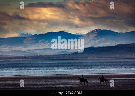 Morecambe, Lancashire, United Kingdom. 18th Mar, 2021. Horse riders riding on the beach at Morecambe iin front of the South Lakeland Fells across Morecambe Bay Credit: PN News/Alamy Live News Stock Photo