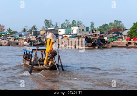 Young Vietnamese woman with conical hat in boat on Can Tho Floating Market, Mekong Delta, Vietnam. Stock Photo