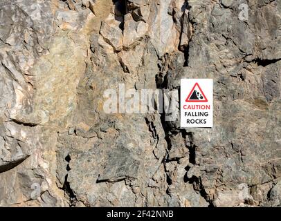CAUTION FALLING ROCKS sign on the side of a vertical limestone cliff.  There is room for text. Stock Photo