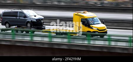 an tow truck with a broken down car speeding on a highway panorama Stock Photo