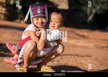 Young boy and his baby brother of Akha tribe kneeling on ground, near Kengtung, Myanmar Stock Photo