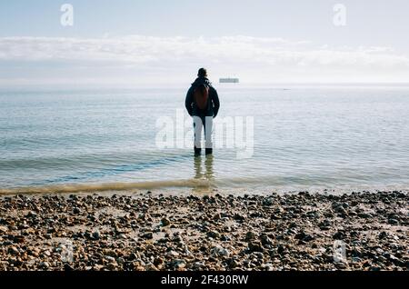 man stood in the ocean thinking, contemplating and dreaming in the sun Stock Photo