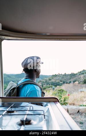 afro american man with  backpack looking at a landscape wit camper van Stock Photo