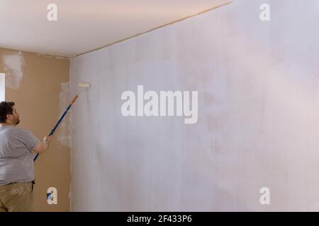 The painter primed the wall with a primer repair the wall after applying gypsum plaster. Stock Photo