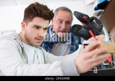 student and teacher in carpentry class using circular saw Stock Photo
