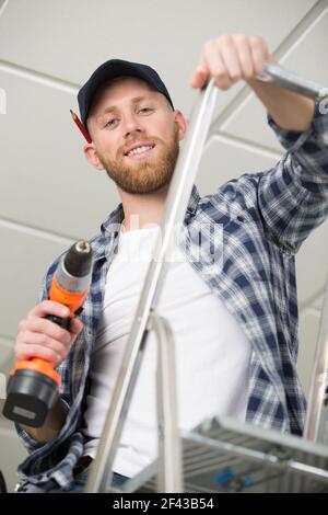 handsome young builder installing light on the ceiling Stock Photo