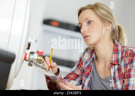 female plumber writing diagnostic on boiler Stock Photo