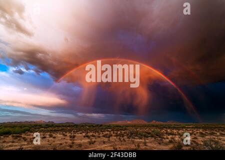 Monsoon storm and desert landscape with a rainbow, virga, and dramatic clouds at sunset near Gila Bend, Arizona Stock Photo