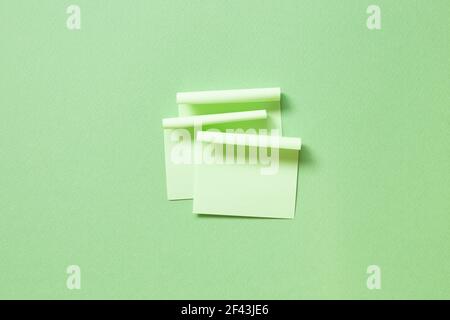 Green memo pad sticky note on green background. top view, copy space Stock Photo