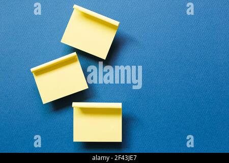 Yellow memo pad sticky note on blue background. top view, copy space Stock Photo