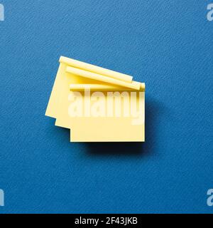 Yellow memo pad sticky note on blue background. top view, copy space Stock Photo