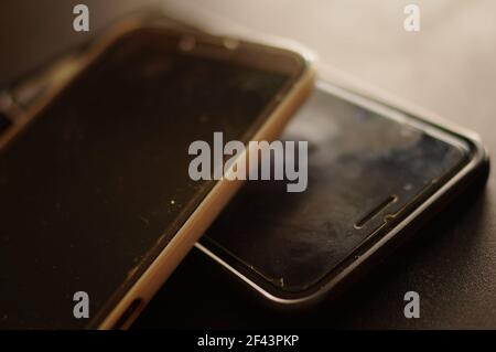 Two used large black cell phones. Protective lcd, with signs of use. Destruction and wear on the screen. Phones in need of service. Stock Photo