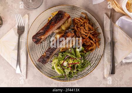 Delicious barbecued ribs seasoned with a spicy basting sauce and served with chopped fresh herbs Stock Photo